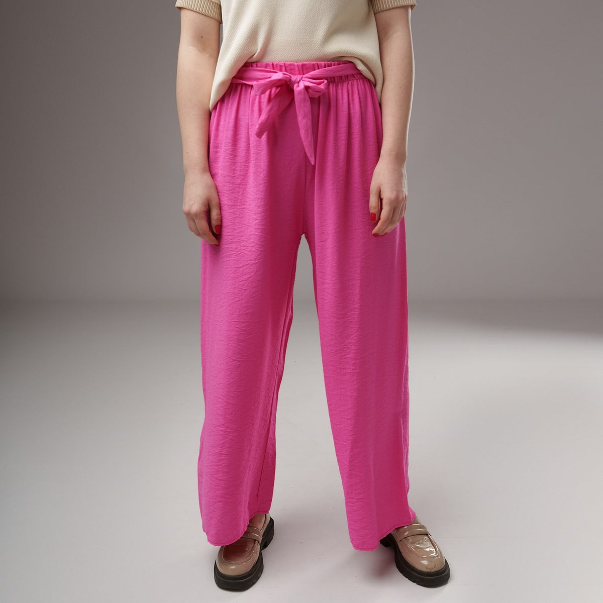 Prim-plan pe talia pantalonilor evazați fucsia din viscoză, cu elastic lat și cordon decorativ, textură ușor creponată.