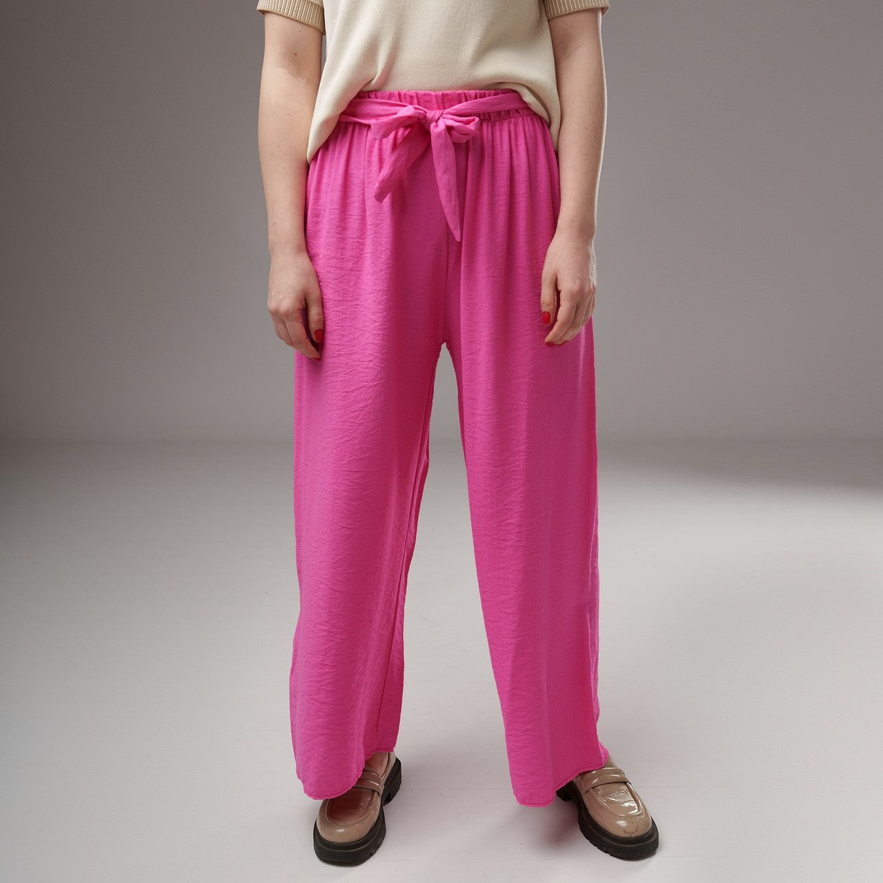 Prim-plan pe talia pantalonilor evazați fucsia din viscoză, cu elastic lat și cordon decorativ, textură ușor creponată.