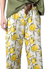 Pantaloni lungi evazați cu imprimeu de lămâi galbene pe fundal alb, detaliu din față cu buzunare laterale