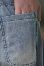 Gros-plan pe buzunarul aplicat al pantalonilor jeans barrel, cu margine verde