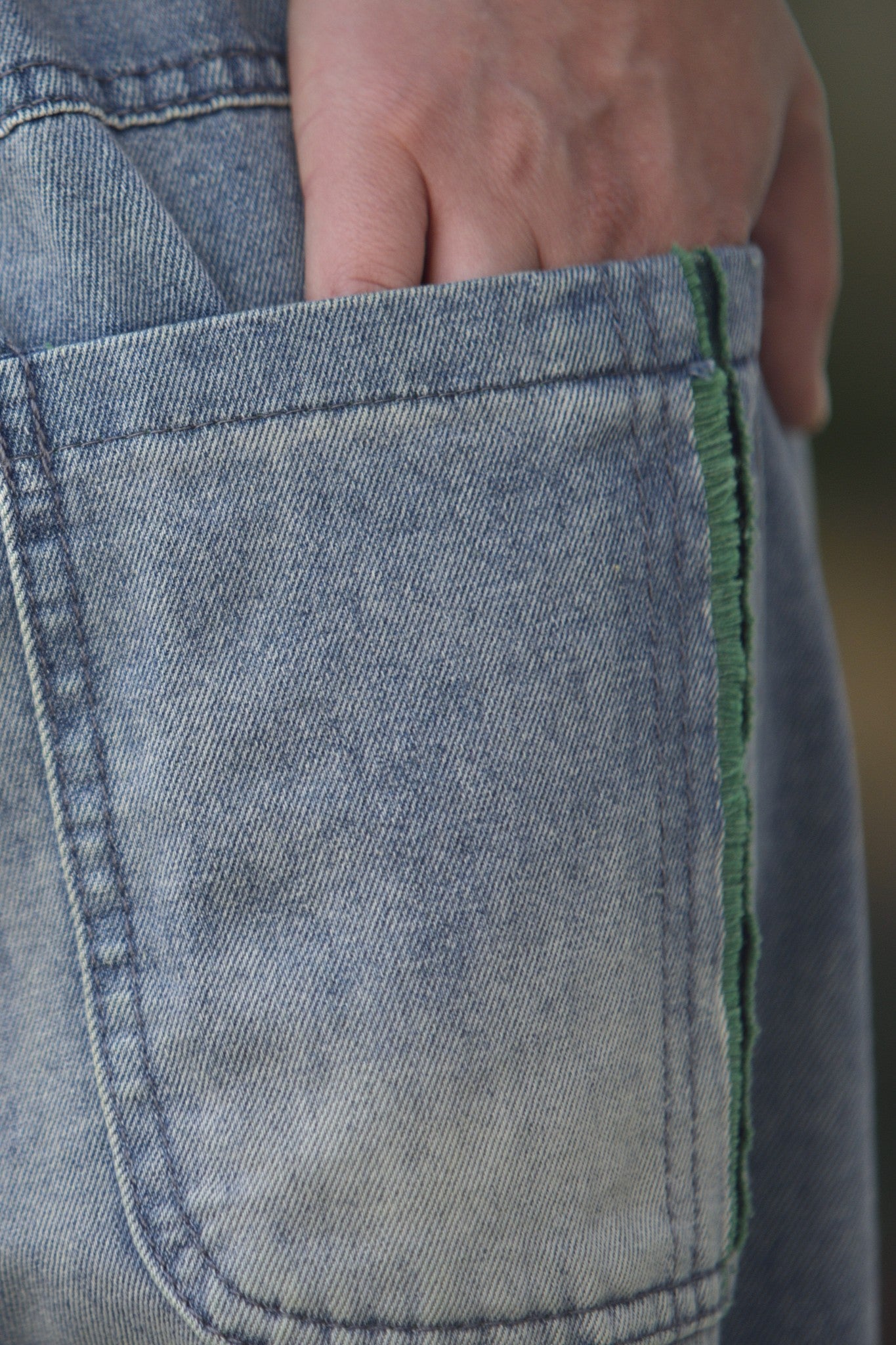 Gros-plan pe buzunarul aplicat al pantalonilor jeans barrel, cu margine verde