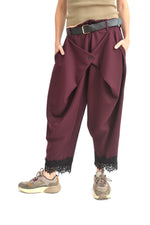 Pantaloni conici tip plic din jerseu bordo, cu tiv decorat cu dantelă neagră, croială lejeră și talie elastică.