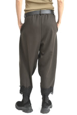 Pantaloni conici maro văzuți din spate, cu croială tip plic și manșete din dantelă.