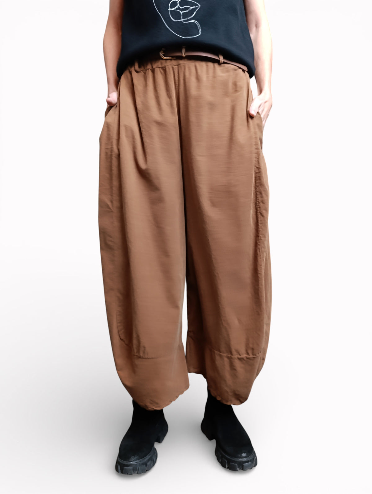 Vedere semiprofil a pantalonilor largi camel din bumbac, cu buzunare laterale și volum amplu pe picior.