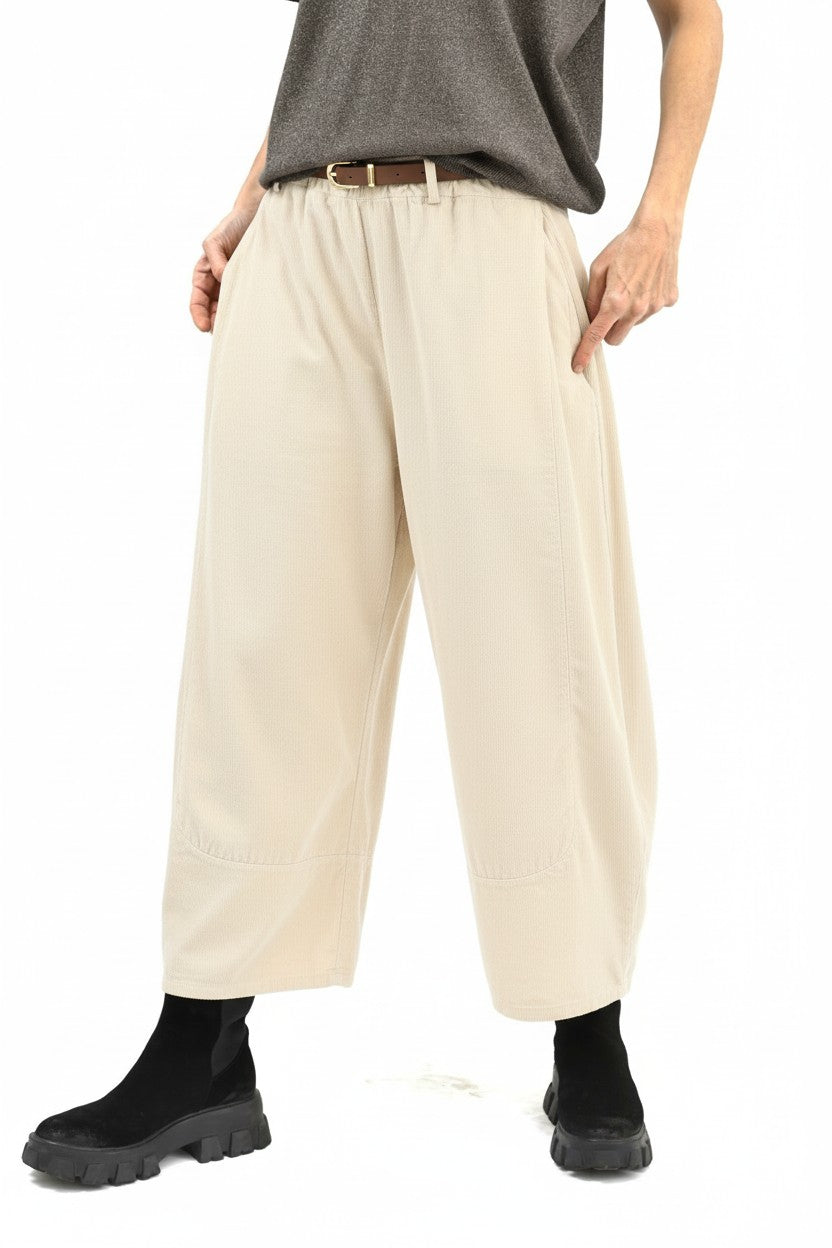 Vedere semiprofil a pantalonilor largi din bumbac, cu buzunare laterale și volum amplu pe picior.