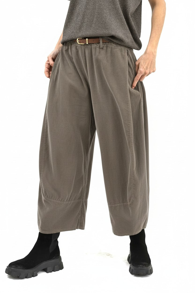 Vedere semiprofil a pantalonilor largi din bumbac, cu buzunare laterale și volum amplu pe picior.