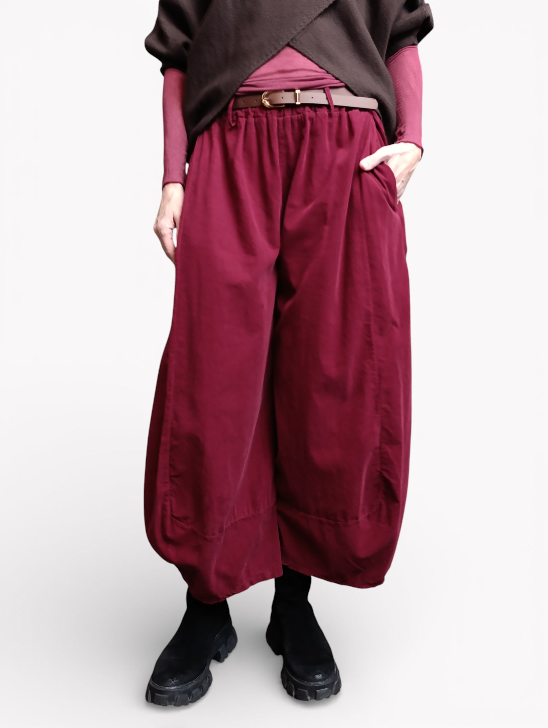 Vedere semiprofil a pantalonilor largi bordo din bumbac, cu buzunare laterale și volum amplu pe picior.