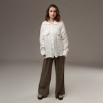 Model purtând pantaloni largi kaki, cu cămașă albă din in, într-un styling lejer și relaxat