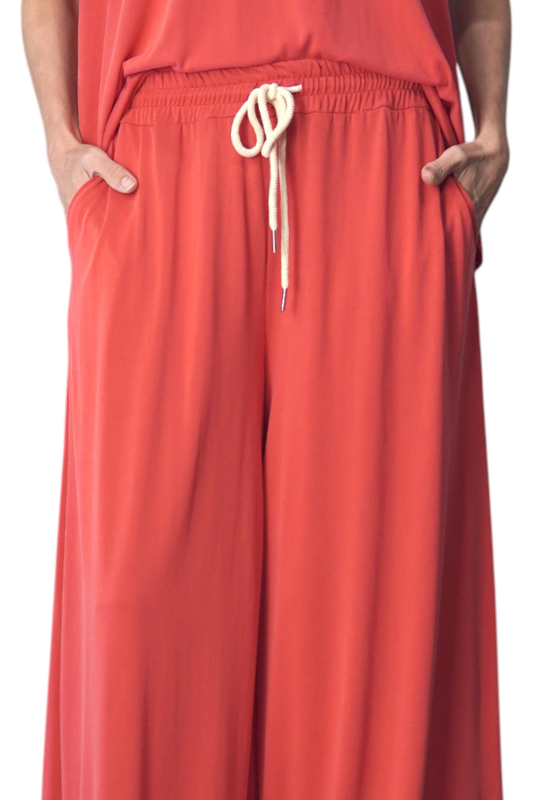 Detaliu din talie al pantalonilor corai, evidențiind șnurul decorativ și materialul fluid