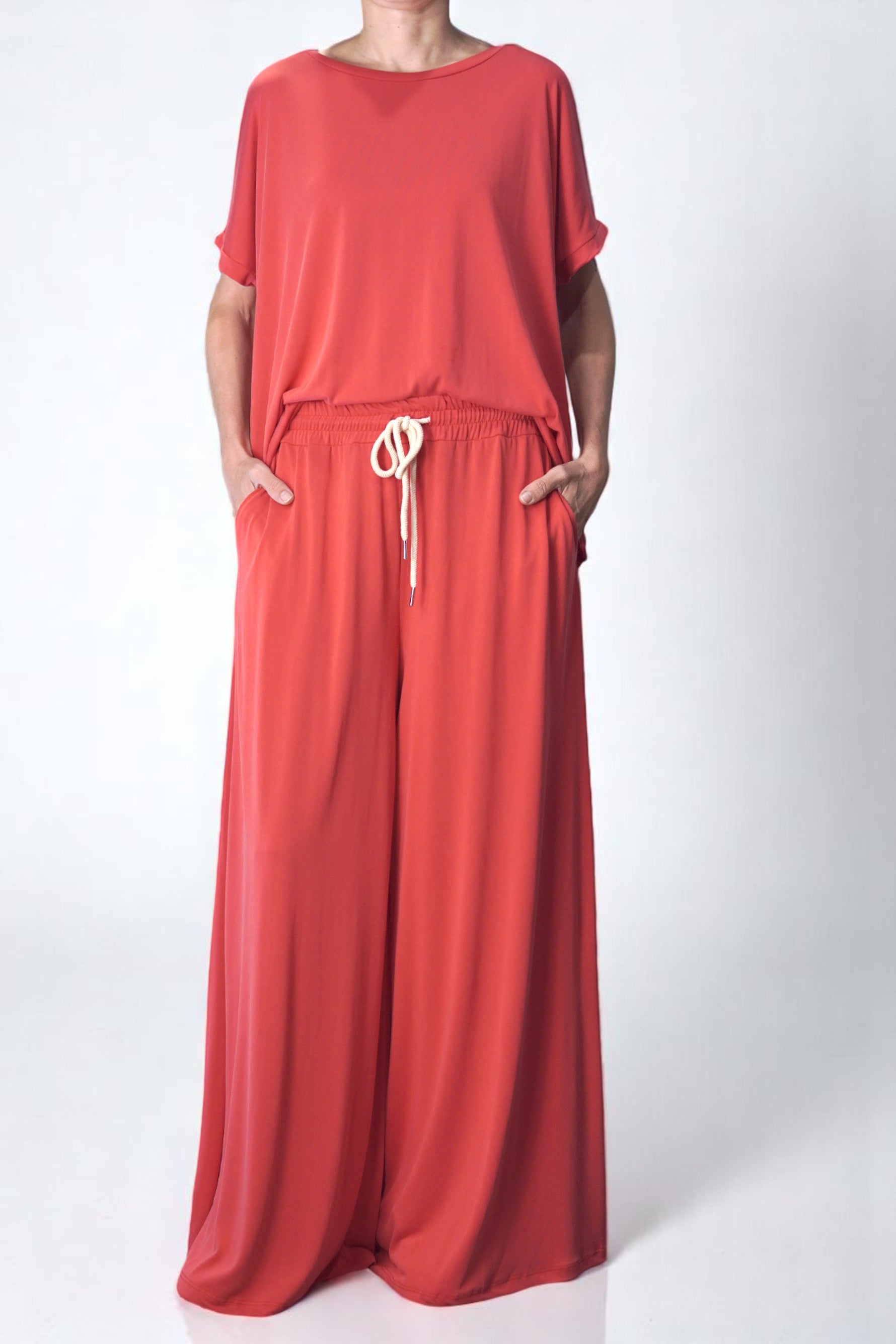 Pantaloni corai lejeri, largi și vaporoși, cu șnur alb în talie și buzunare laterale