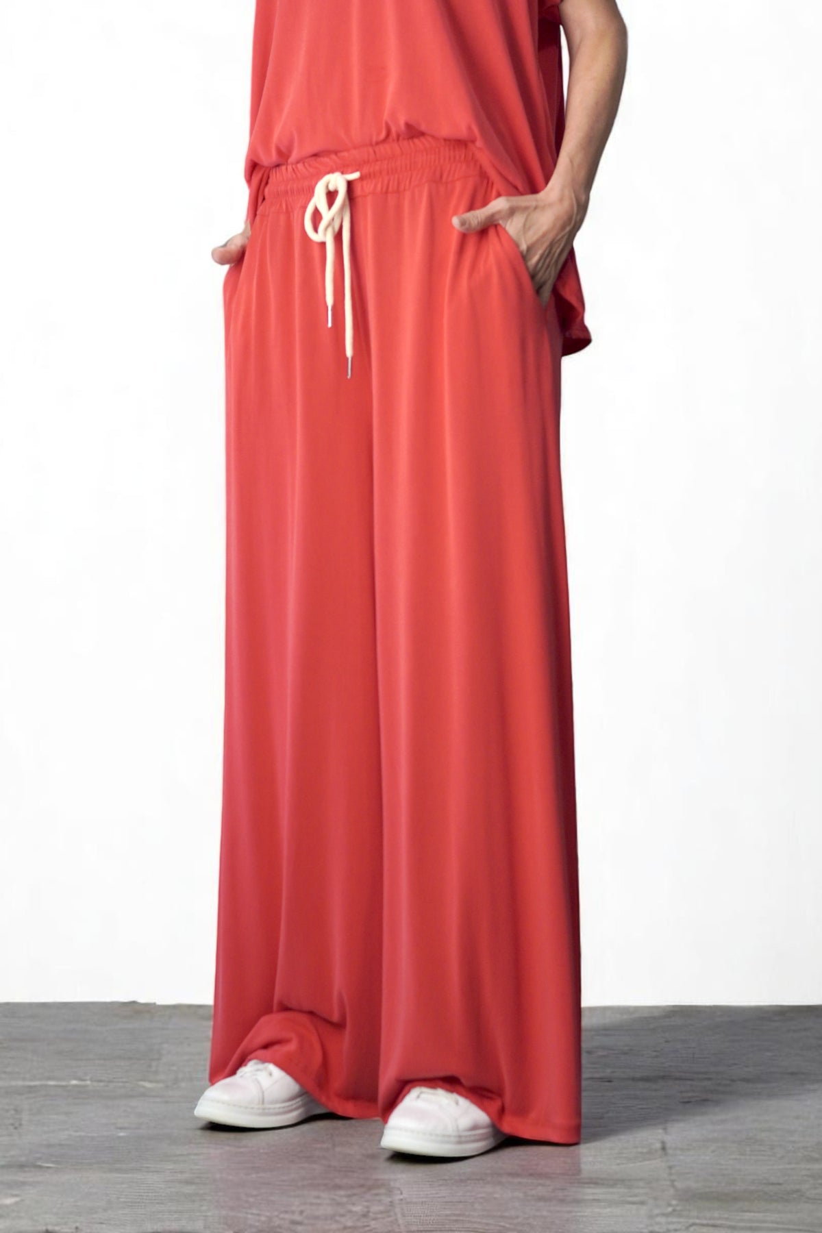 Pantaloni corai vaporoși, văzuți din lateral, cu croială amplă și cădere lină