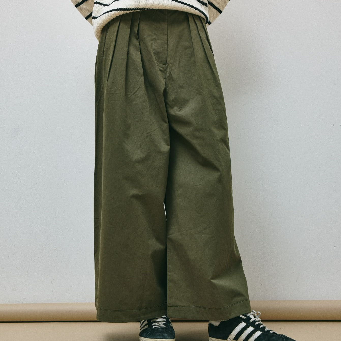 Pantaloni largi de culoare verde-oliv din bumbac structurat, cu talie înaltă și croială amplă, văzuți din față.