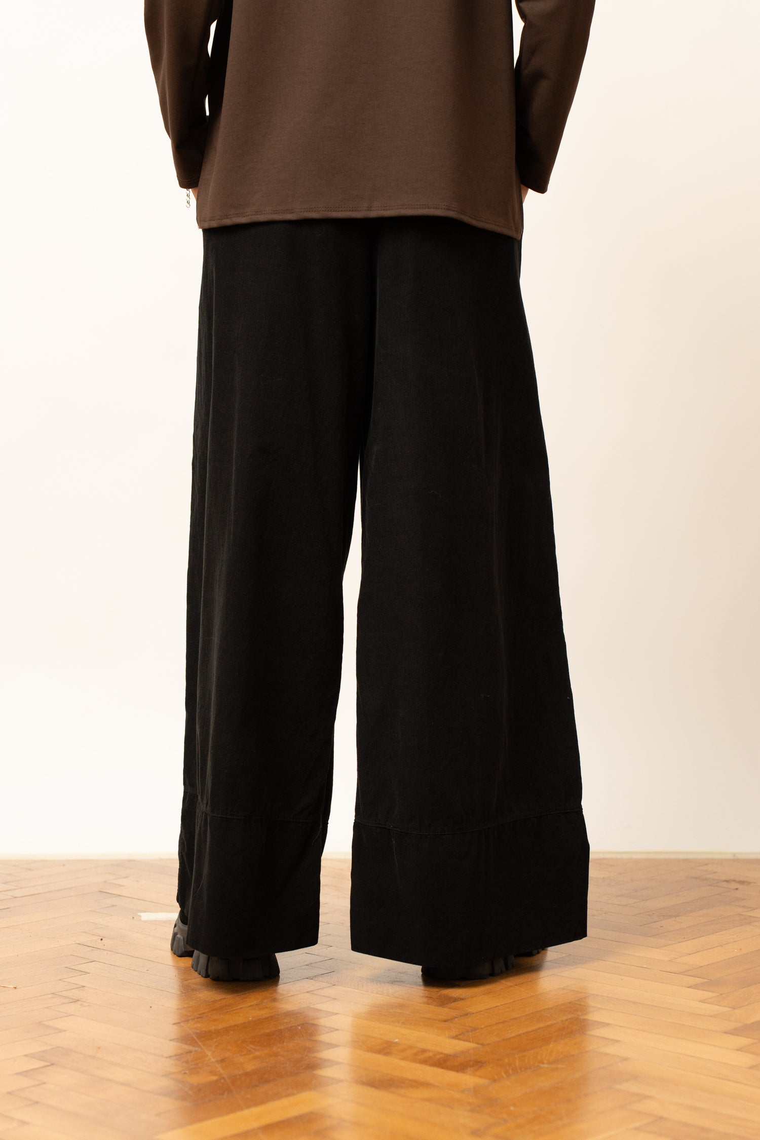 Pantaloni largi negri cu talie elastică, vedere din spate.