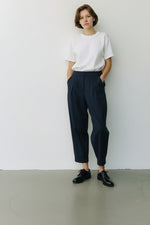 Pantaloni lejeri cu croială relaxată, culoare bleumarin, purtați cu top deschis și pantofi casual.