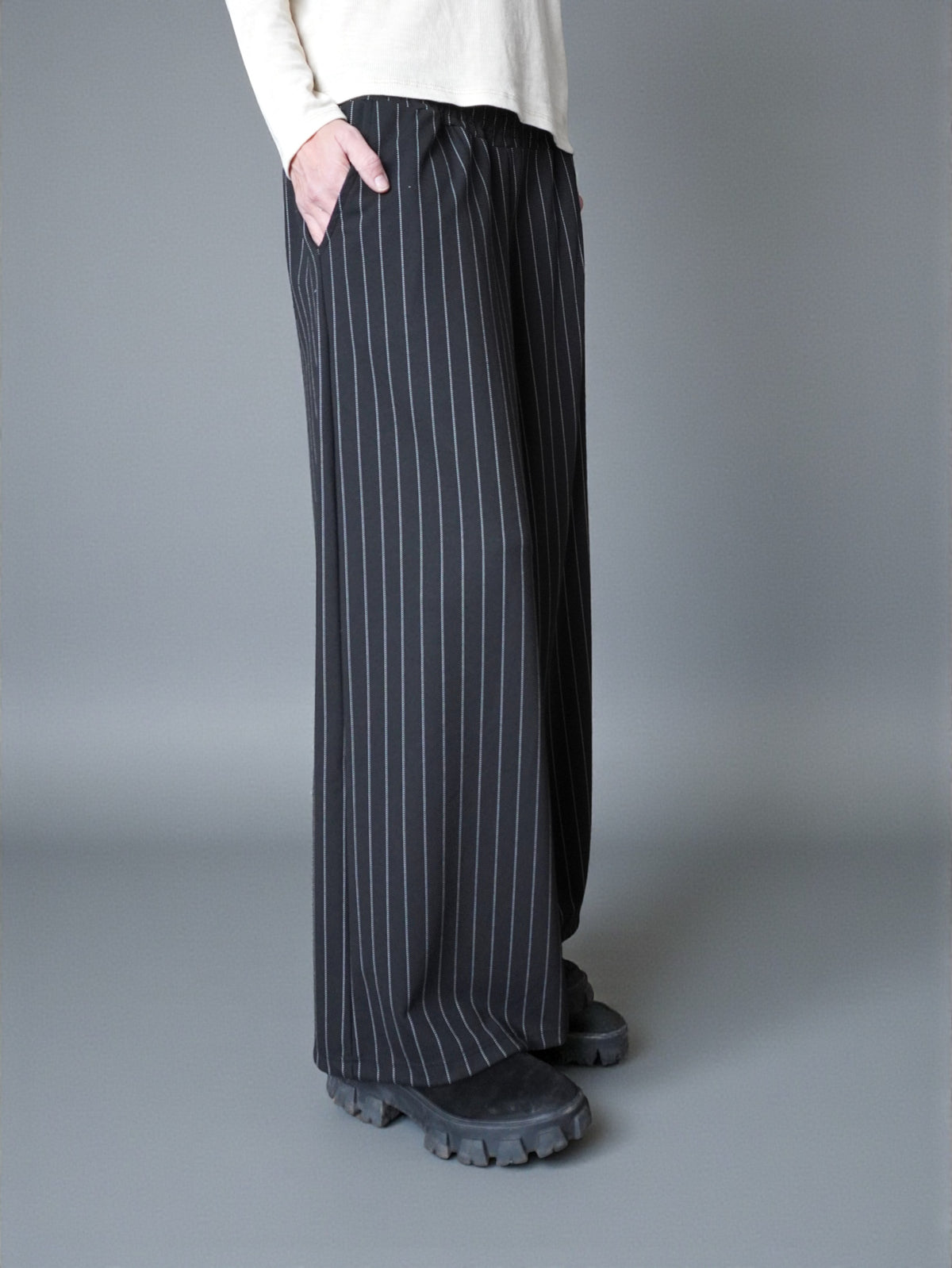 Vedere laterală a pantalonilor largi cu dungi, evidențiind fluiditatea materialului.