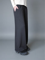 Vedere laterală a pantalonilor largi cu dungi, evidențiind fluiditatea materialului.