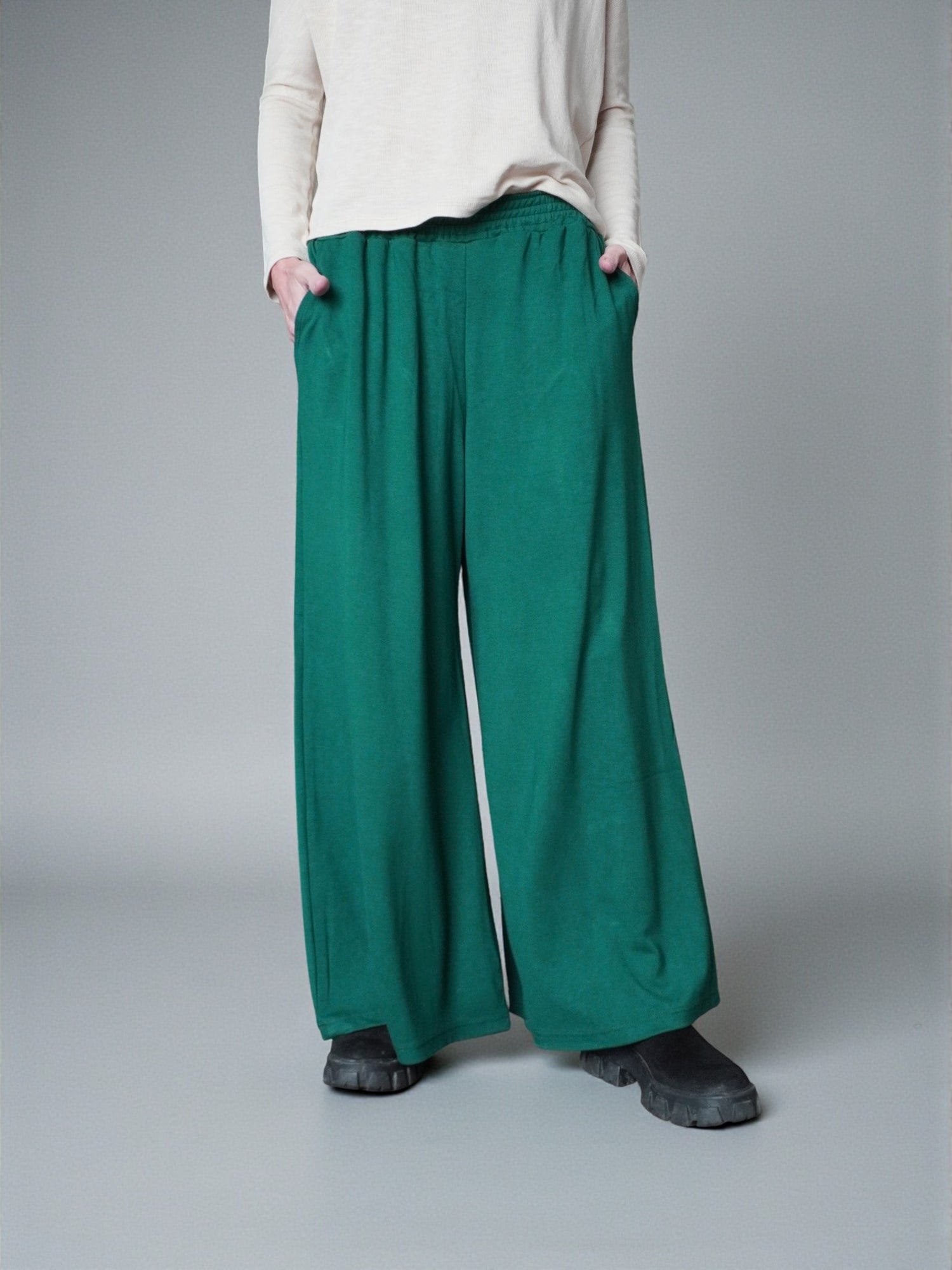 Pantaloni palazzo verzi surprinși din profil, evidențiind lățimea piciorului.