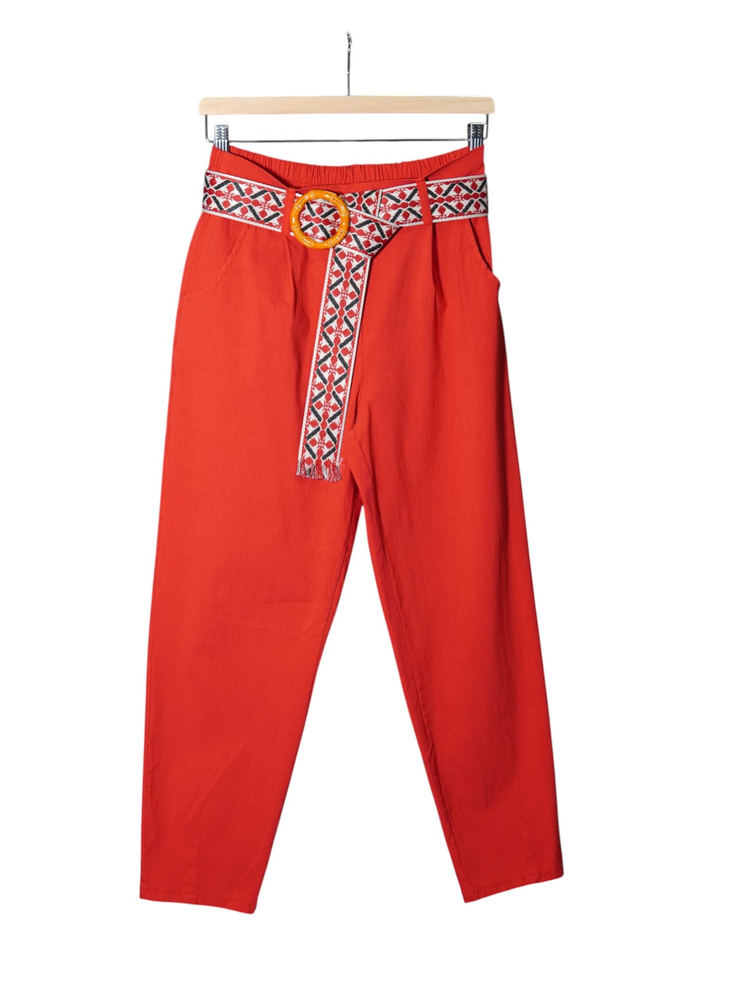 Pantaloni roșii cu croială conică și curea etnică roșie cu alb, completată de o cataramă rotundă decorativă.