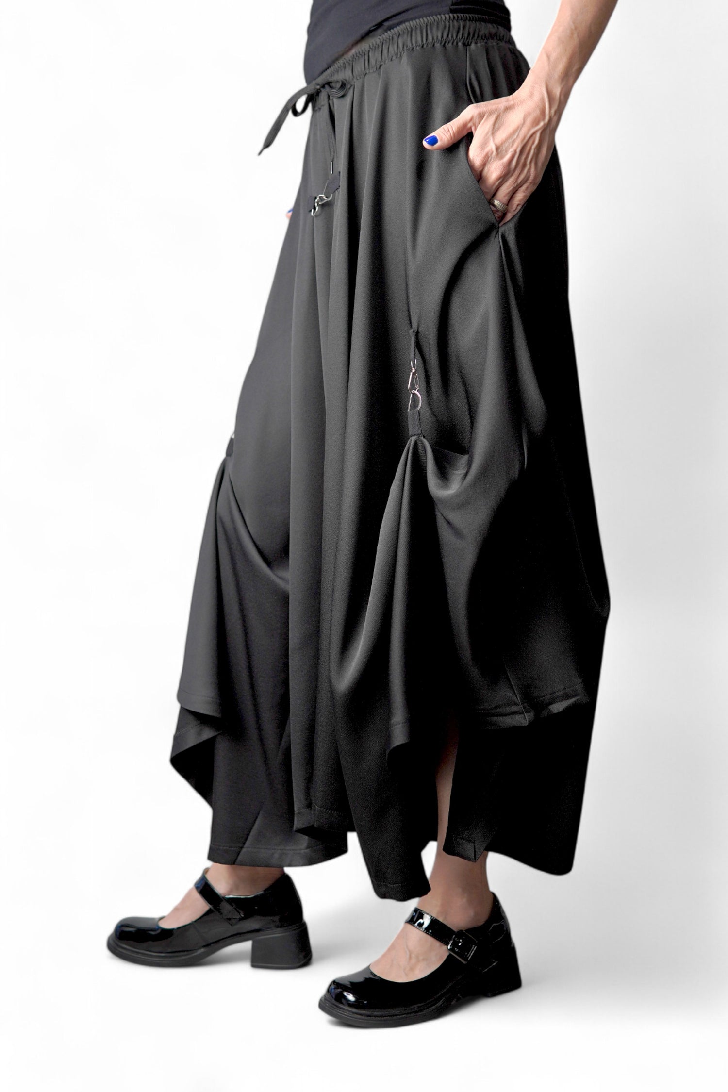 Vedere laterală a pantalonilor satinați negri, cu design amplu și buzunare adânci