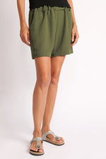 Pantaloni scurți kaki lejeri cu buzunare, vedere din semiprofil pe model.