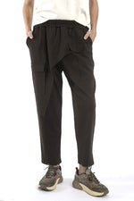 Pantaloni maro cu talie elastică și croială lejeră, purtați cu tricou deschis la culoare, vedere frontală.