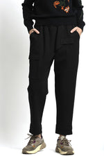 Pantaloni negru cu talie elastică și croială lejeră, purtați cu tricou deschis la culoare, vedere frontală.