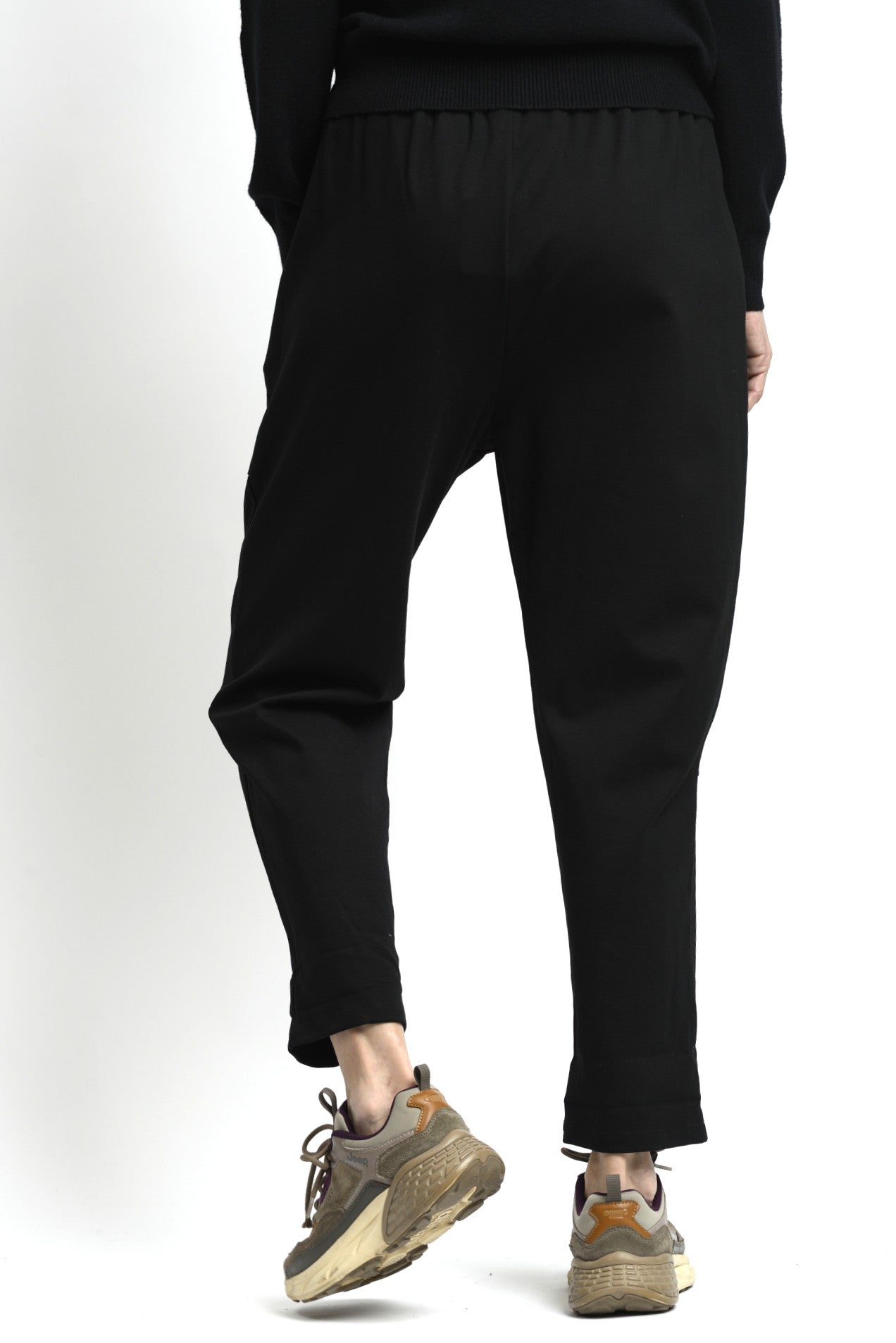 Pantaloni negru cu talie elastică și croială lejeră, purtați cu tricou deschis la culoare.