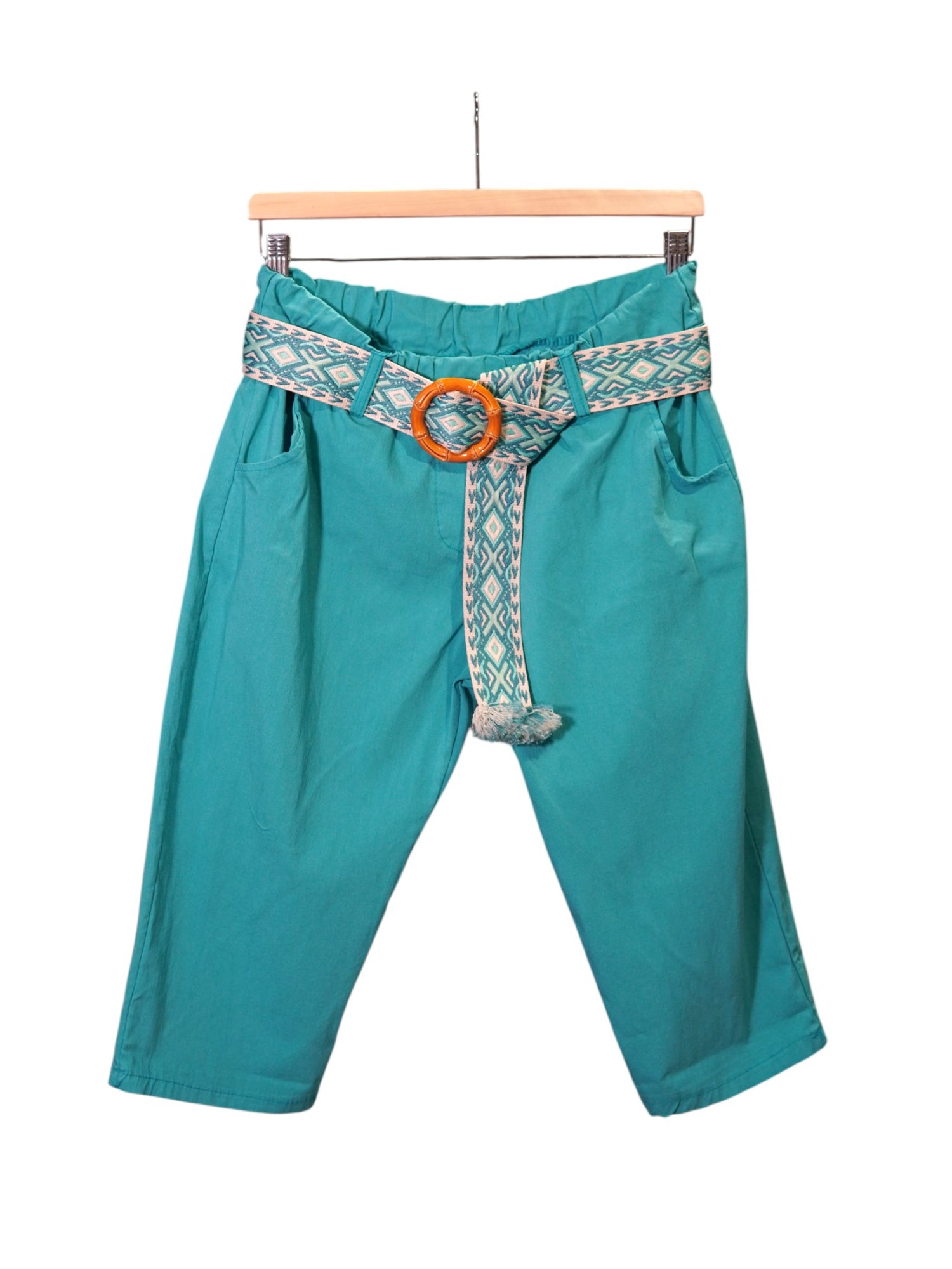 Pantaloni trei sferturi turcoaz, cu buzunare laterale, curea lată cu motive geometrice și detalii cu franjuri decorative.