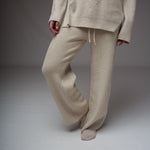 Pantaloni bej din tricot soft, croială lejeră, talie elastică cu șiret, textură cu striații, vedere pe model.