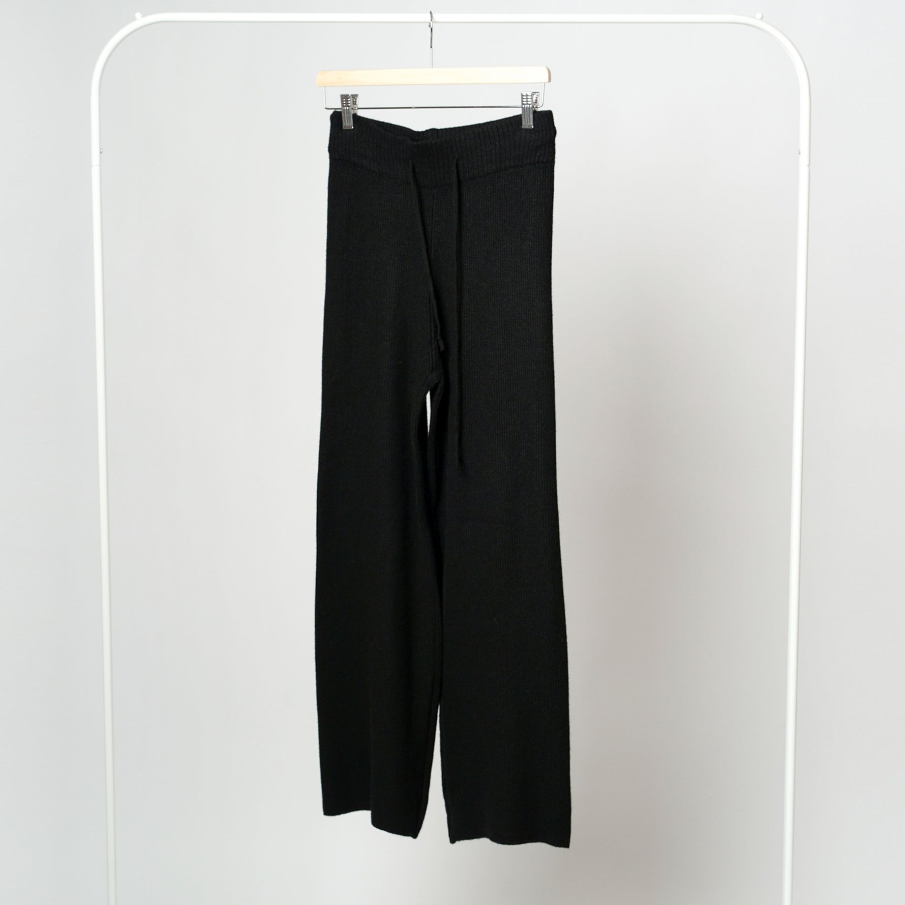 Pantaloni negri din tricot soft pe umeraș, talie elastică, textură moale și călduroasă.