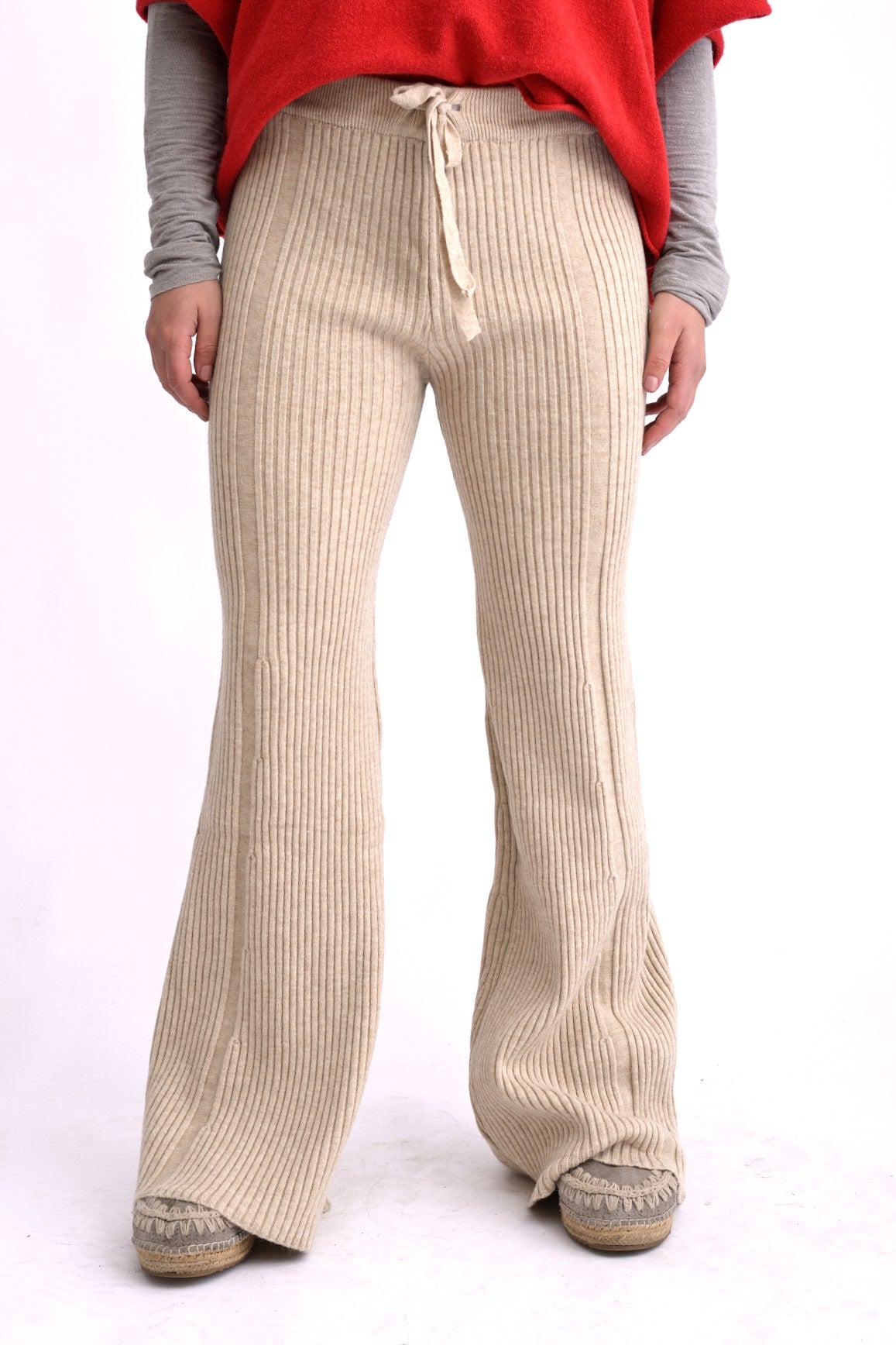 Pantaloni bej tricotati, evazați, cu model ajurat și textură moale, fotografiați lateral.