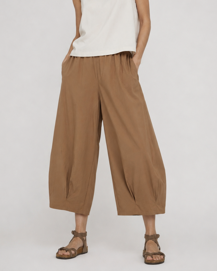 Pantaloni evazați bej cu pliuri la tiv, vedere frontală. All Above Boutique.
