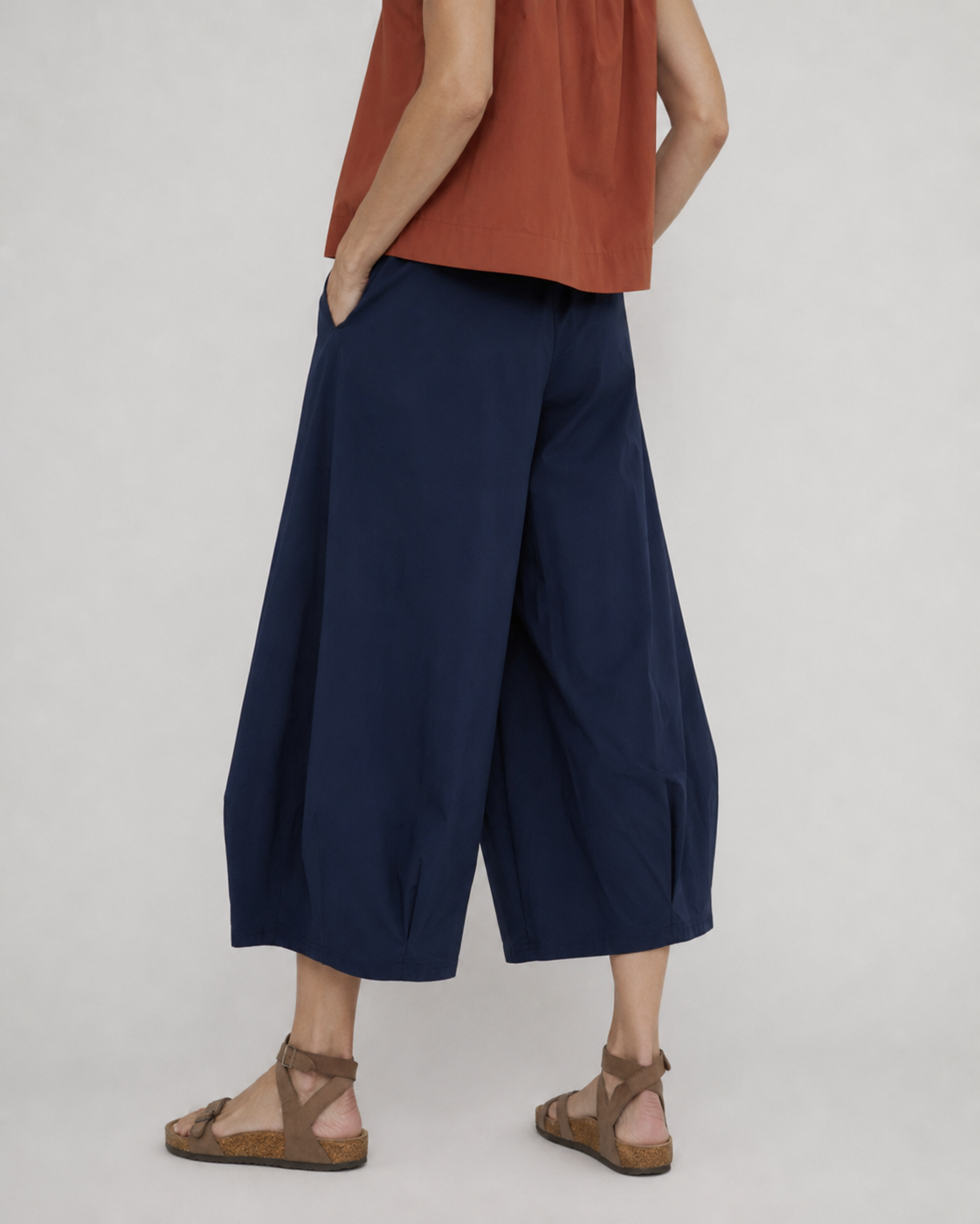 Pantaloni evazați bleumarin cu pliuri la tiv, vedere din spate. All Above Boutique.
