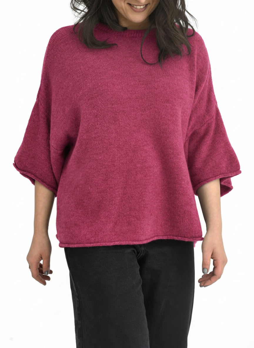 Pulover oversize din amestec cu alpaca, nuanță roz zmeură, cu mânecă scurtă și croială amplă, purtat cu pantaloni negri.