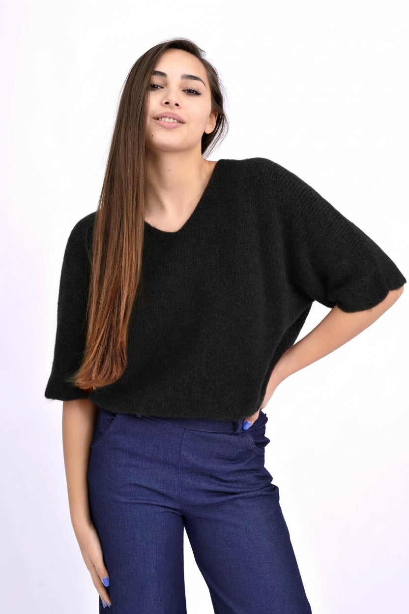 Pulover negru din alpaca cu decolteu în V și umeri căzuți, croială lejeră, purtat pe model.