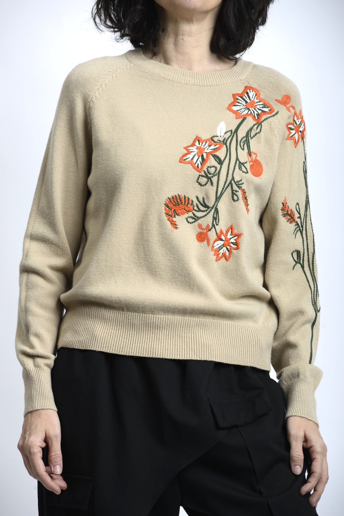 Detaliu broderie florală colorată pe pulover, cu finisaj atent și contrast subtil.