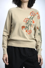 Detaliu broderie florală colorată pe pulover, cu finisaj atent și contrast subtil.