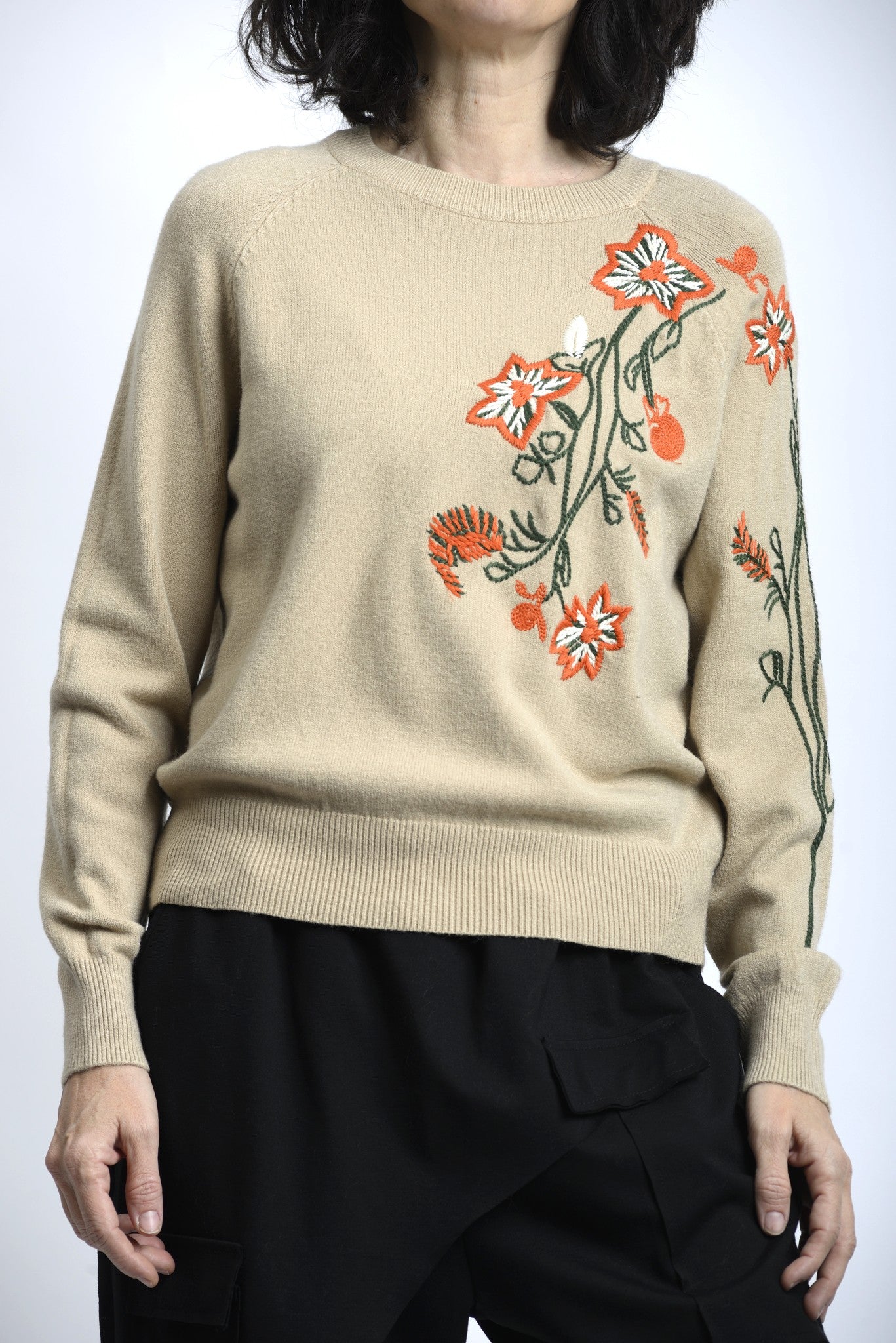 Detaliu broderie florală colorată pe pulover, cu finisaj atent și contrast subtil.