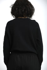 Detaliu broderie florală colorată pe pulover, cu finisaj atent și contrast subtil.