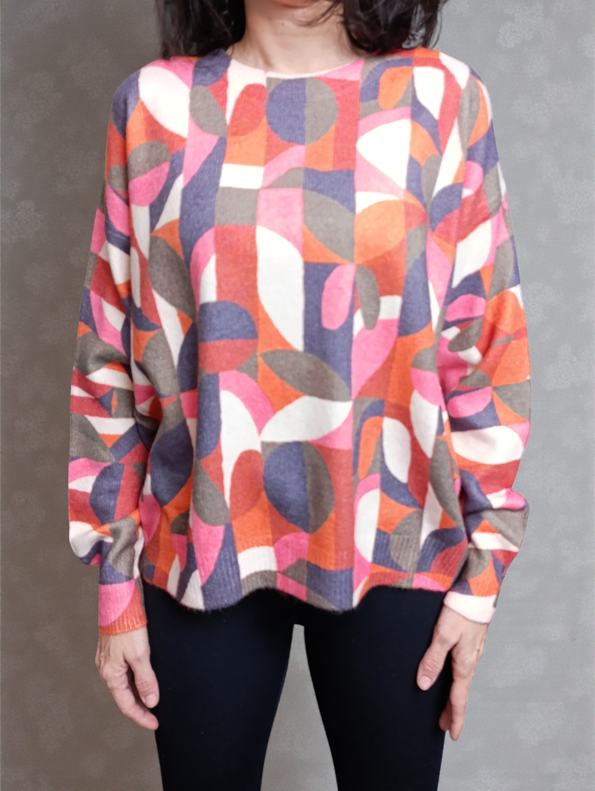 Detaliu de textură al puloverului colorat cu model geometric, evidențiind materialul moale și imprimeul abstract.