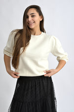 Pulover crem cu umeri bufanți și croială lejeră, realizat dintr-un amestec de viscoză și poliamidă.
