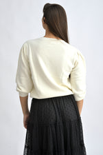 Pulover crem cu umeri bufanți și croială lejeră, realizat dintr-un amestec de viscoză și poliamidă.