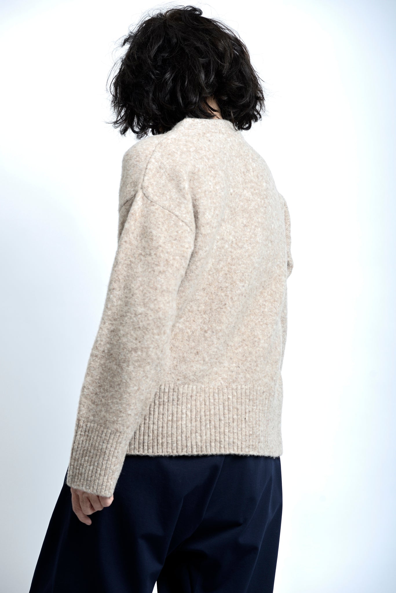 Vedere din spate a puloverului bej cu eșarfă integrată, croială relaxată și tiv elastic.