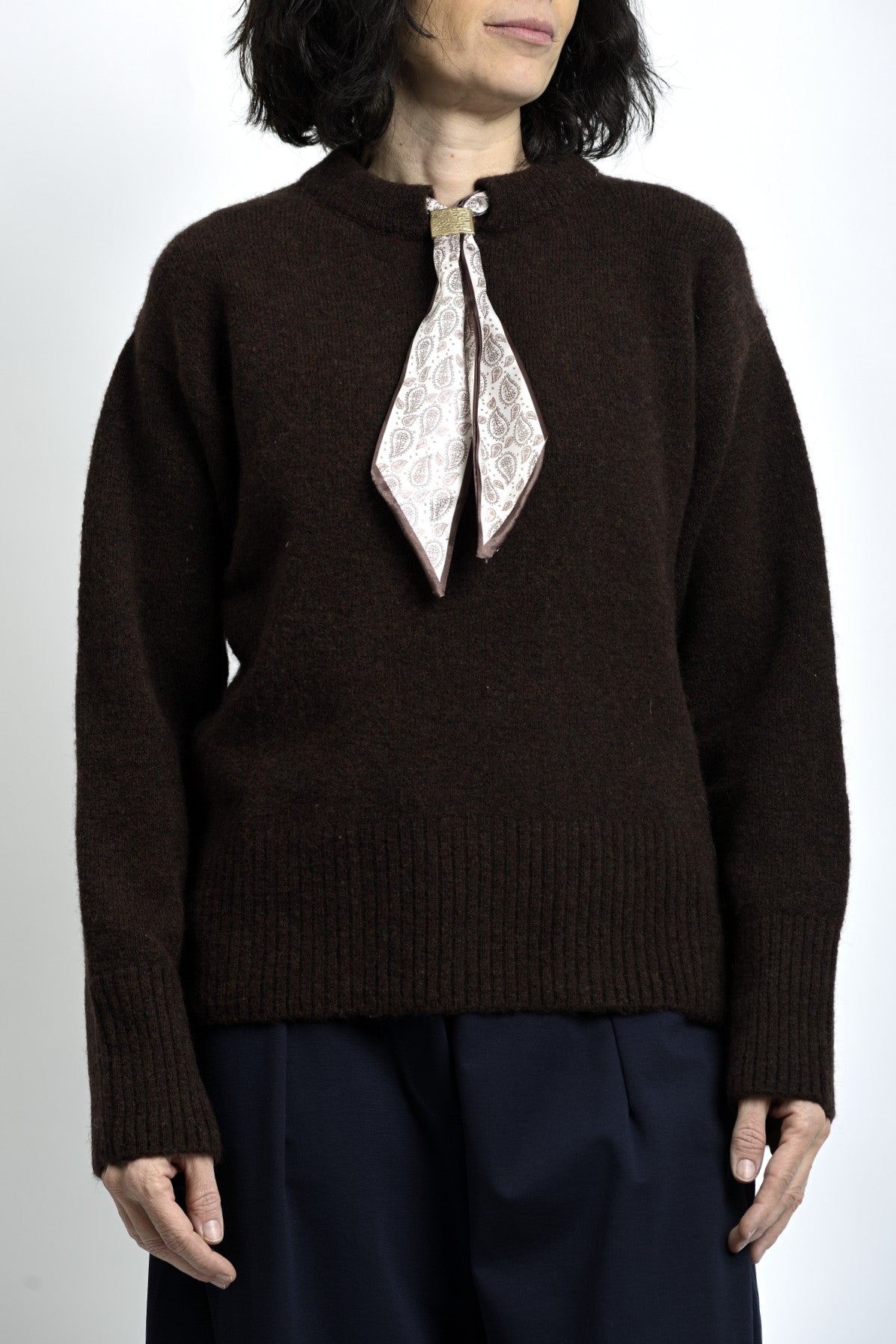 Pulover maro închis cu eșarfă decorativă la gât, textură tricotată și linie clasică.