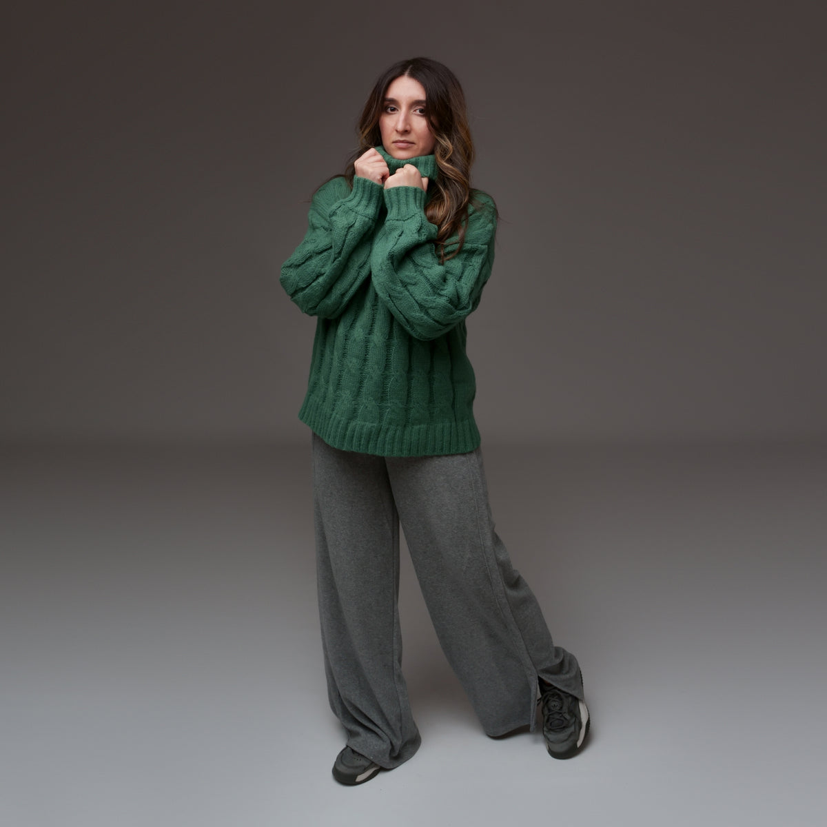Pulover verde cu mâneci lungi și guler înalt, purtat cu pantaloni lejeri, văzut din față întreagă