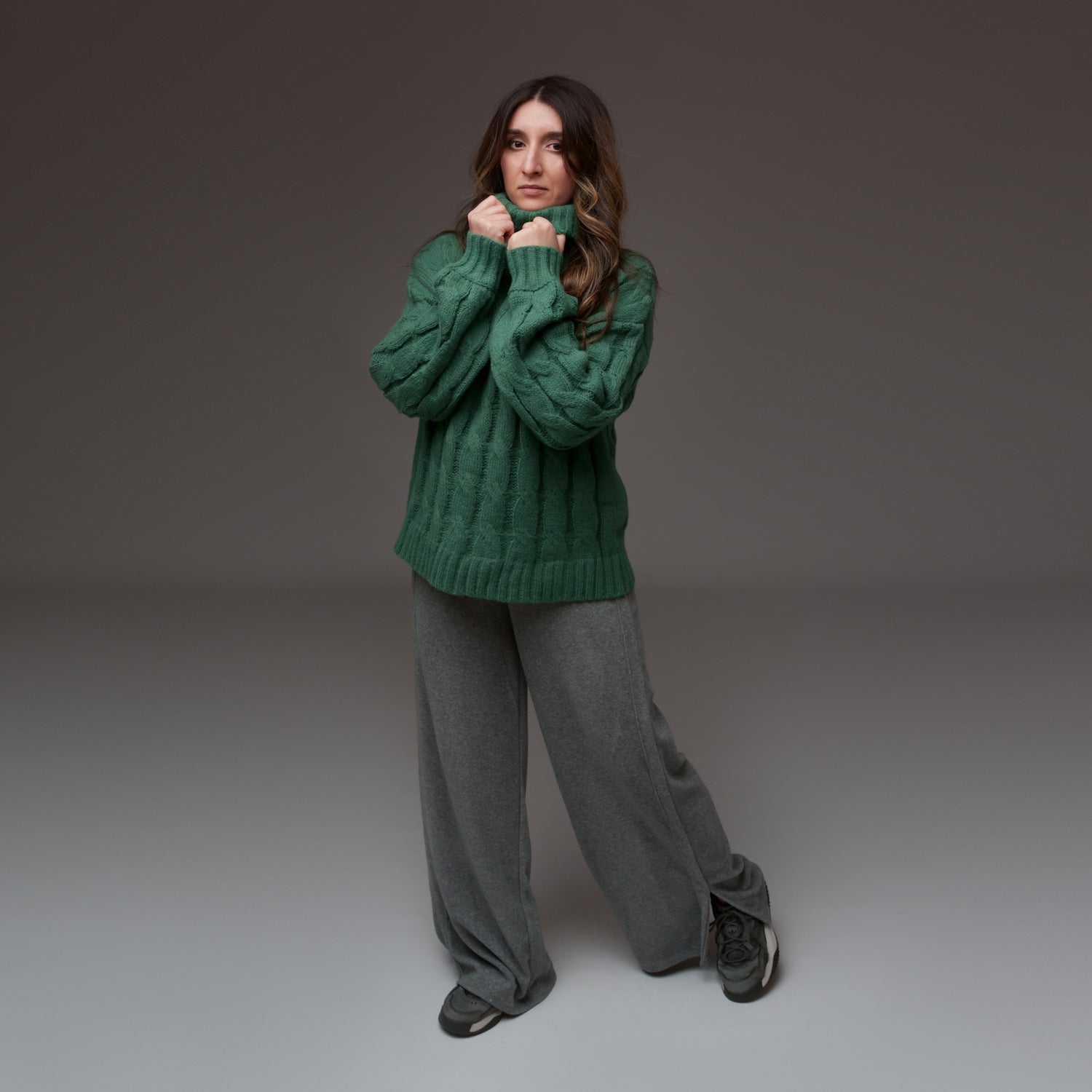 Pulover verde cu mâneci lungi și guler înalt, purtat cu pantaloni lejeri, văzut din față întreagă