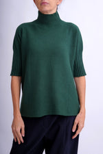 Pulover verde închis cu guler înalt tip funnel, mâneci scurte și croială lejeră din lână moale, cu detalii nervurate la guler și manșete.