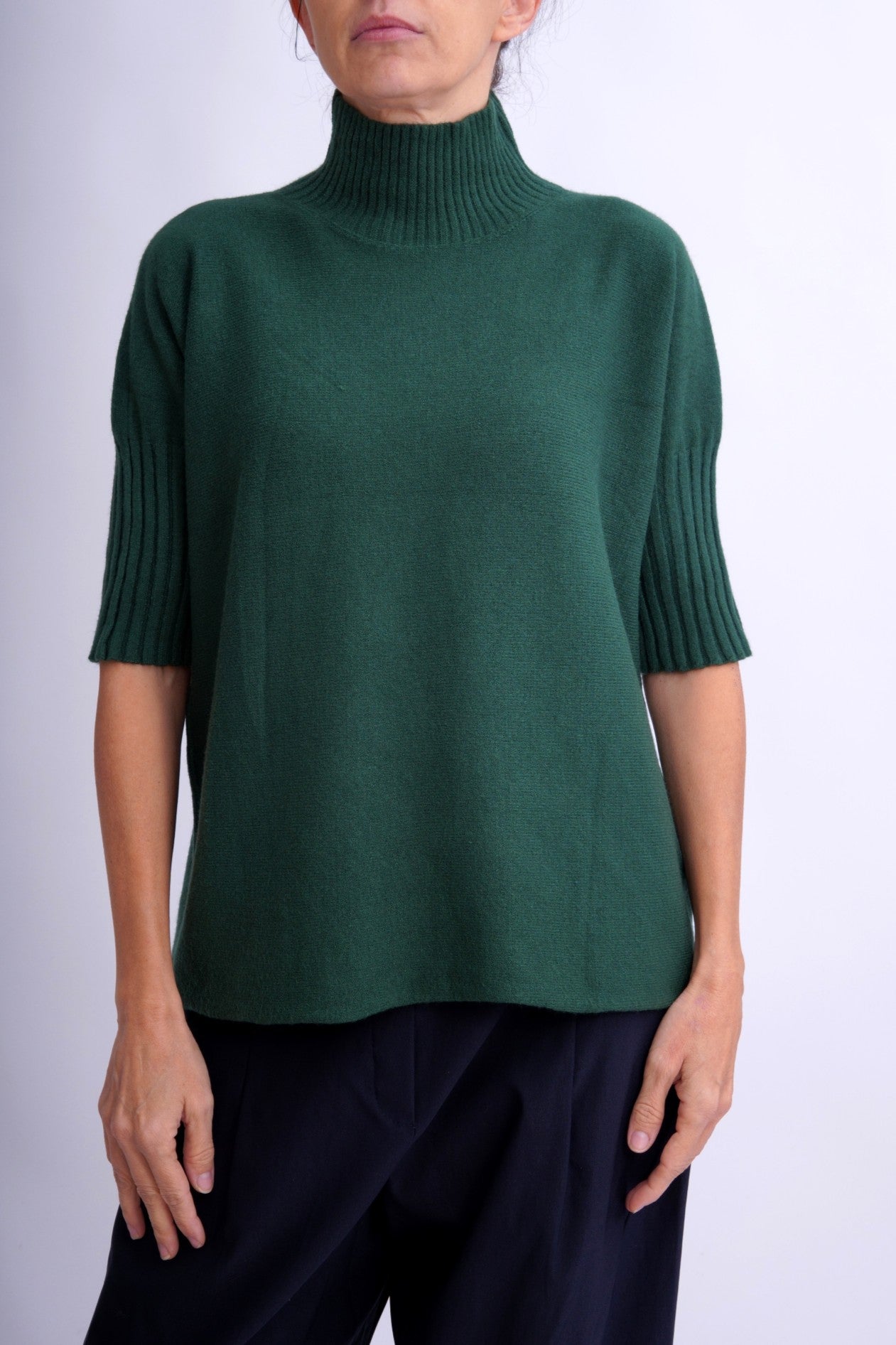 Pulover verde închis cu guler înalt tip funnel, mâneci scurte și croială lejeră din lână moale, cu detalii nervurate la guler și manșete.