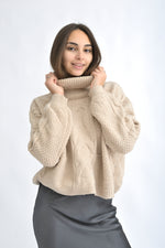 Pulover bej tricotat gros cu model bob de orez și torsade, vedere frontală pe model, croială lejeră și guler înalt.