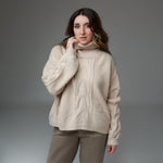 Pulover bej tricotat gros cu model bob de orez și torsade, vedere frontală pe model, croială lejeră și guler înalt.